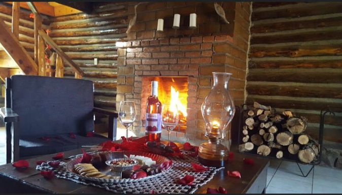 Sala de estar acogedora con chimenea encendida y decoración romántica de pétalos de rosa.