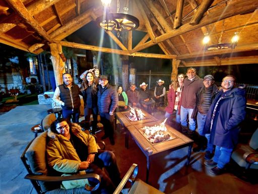 Grupo de personas reunidas alrededor de una fogata en un espacio al aire libre.