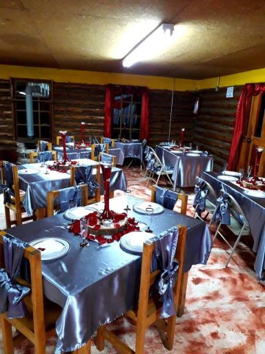 Comedor decorado con mesas elegantes y manteles plateados, ambiente acogedor y cálido.